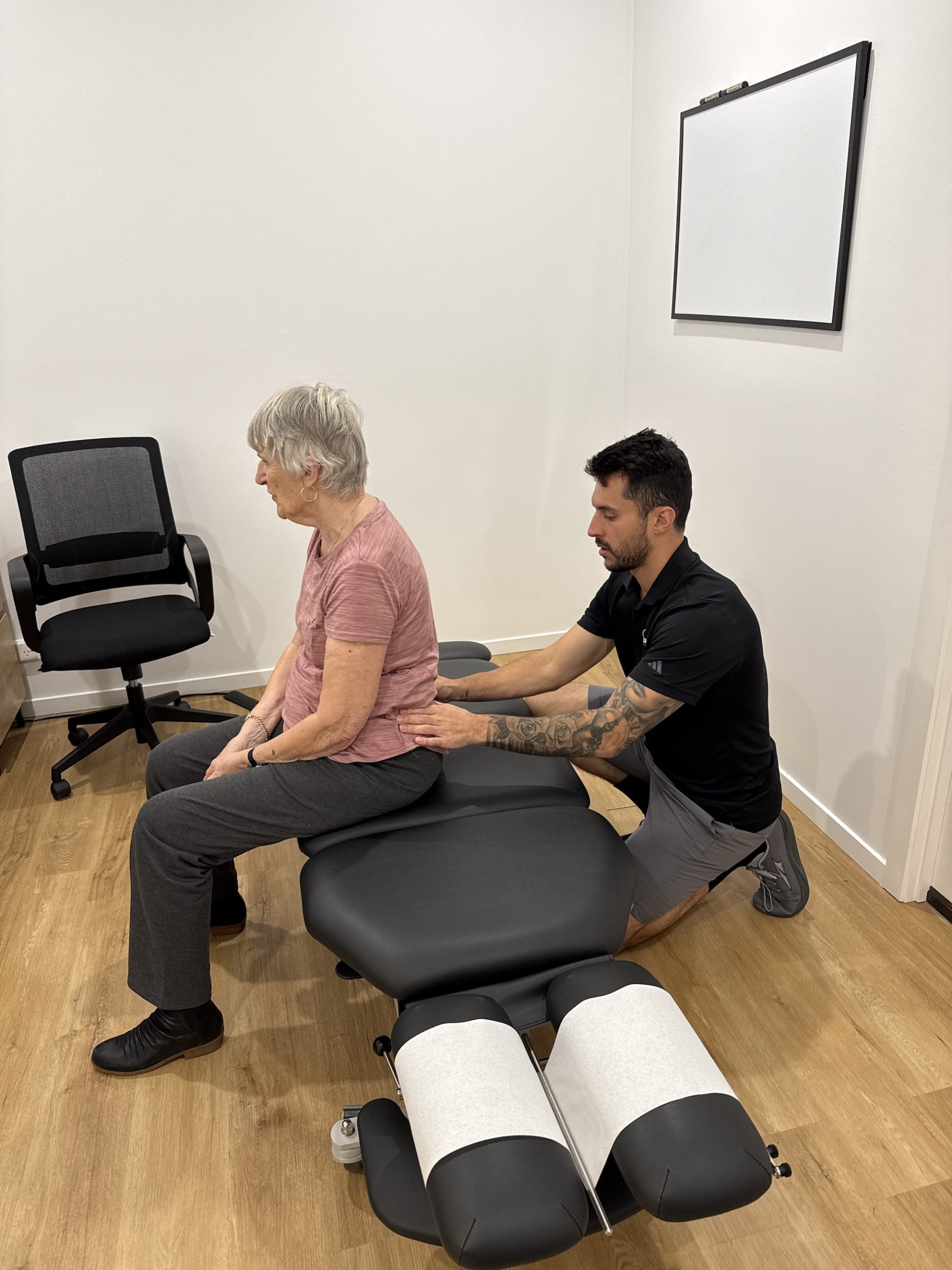 Chiropractor performing a sacroiliac joint (SIJ) assessment on an elderly patient in clinic